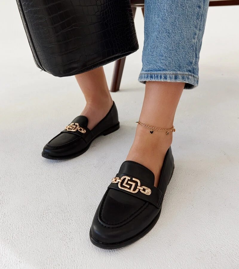 Schwarze Mokassins verziert mit einer Kette von Kuens